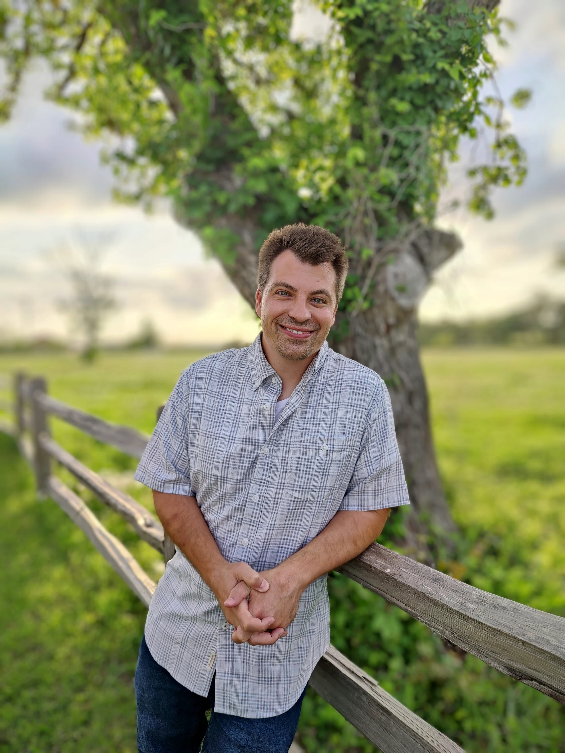 Aaron outdoors at a fence in a field